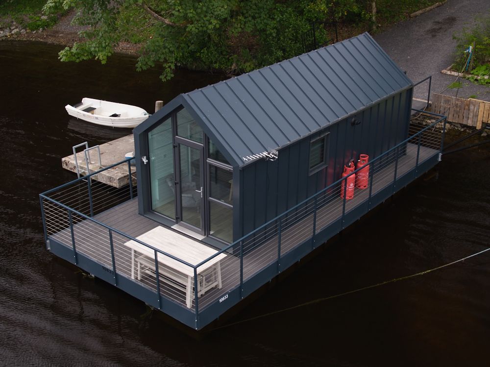 An aerial view of a small house floating on top of a body of water.