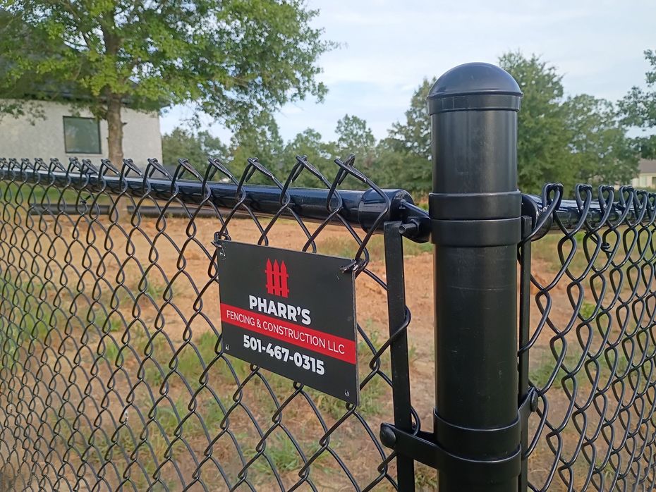 Chain-link fence with black post and red business sign in front of a building.