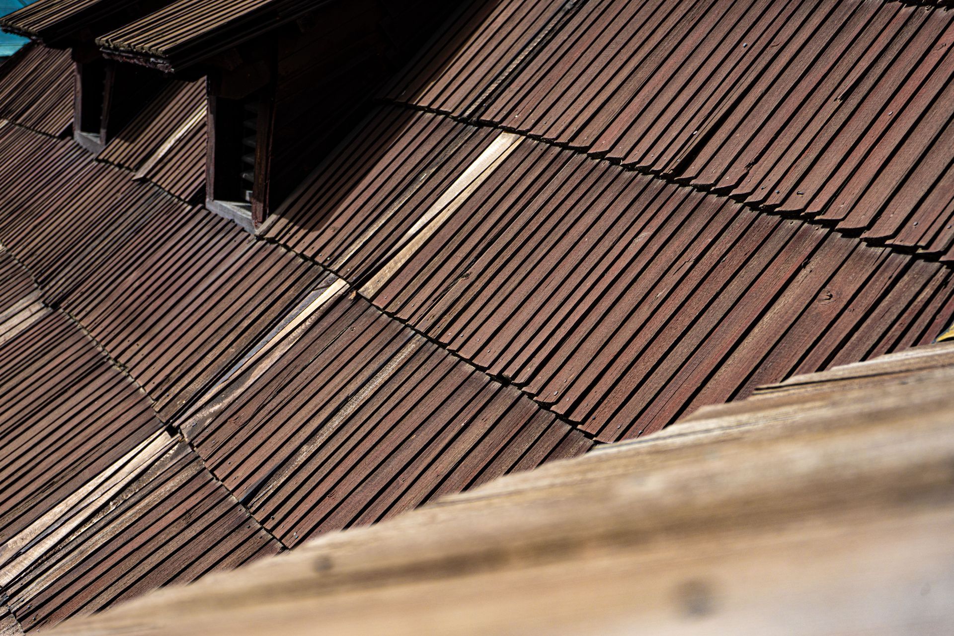 Rust-colored corrugated metal roof with dormer windows and a blurred beige foreground edge
