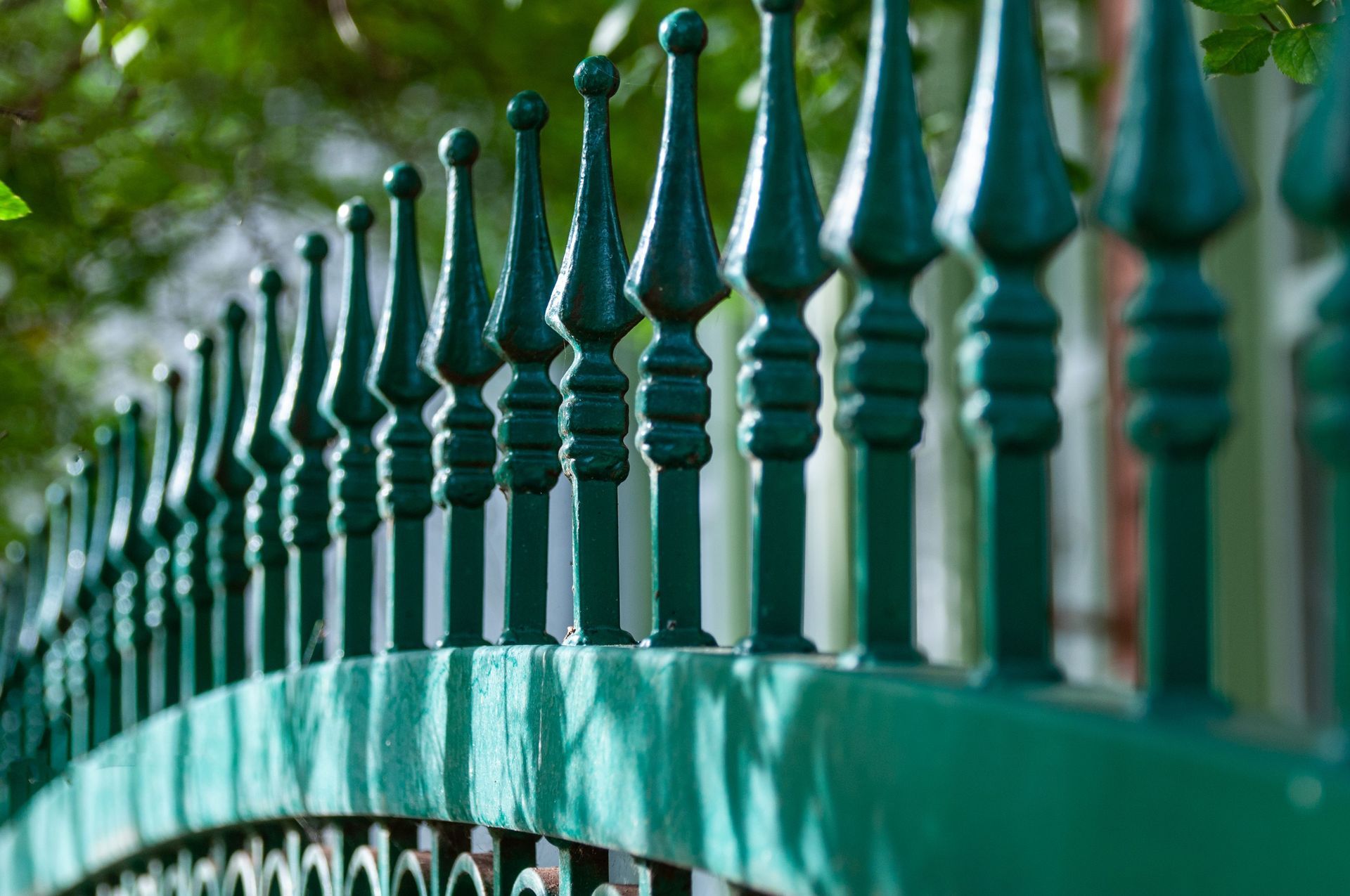 Green metal fence with pointed finials in shallow focus, outdoors