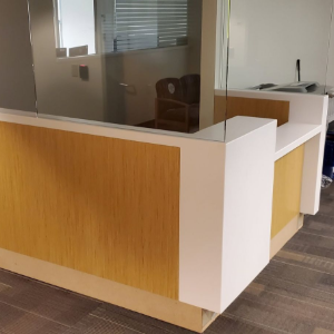 Reception desk with wood panels and glass partition in a modern office lobby