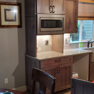 Kitchen nook with brown cabinets, built-in microwave, and a window over the countertop.