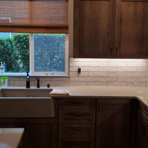 Modern kitchen with dark wood cabinets, white subway tile backsplash, farmhouse sink, and window blinds