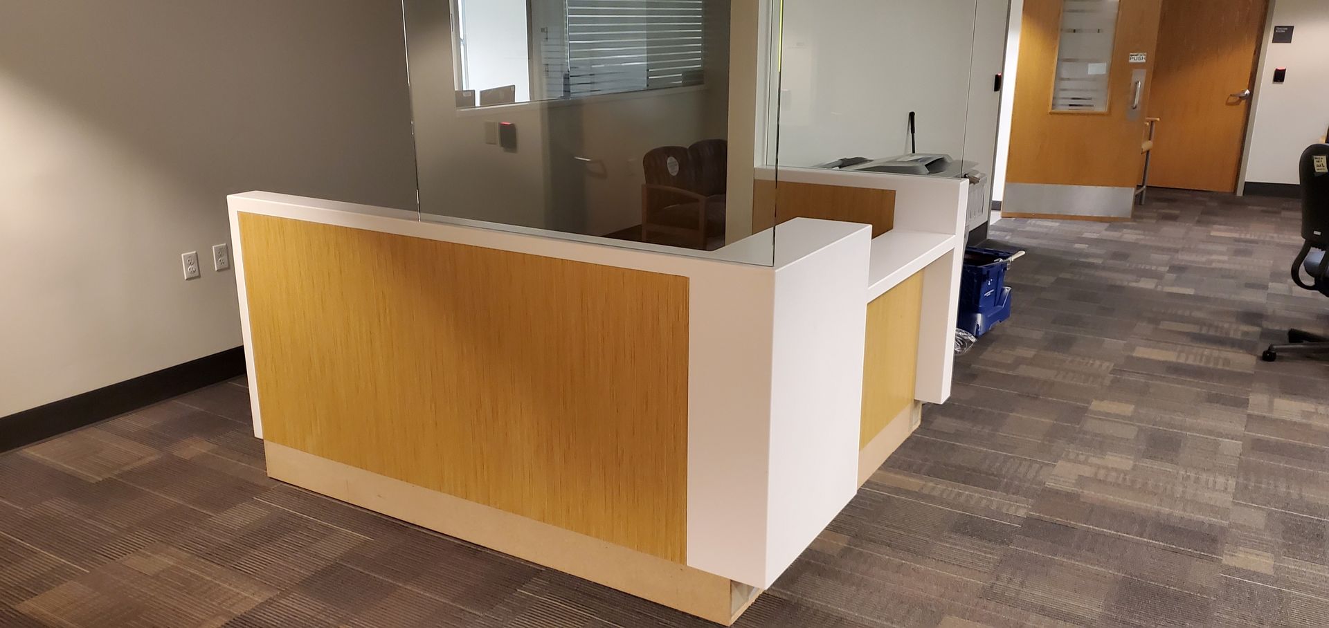Reception desk with wood panels and white trim in an office lobby area