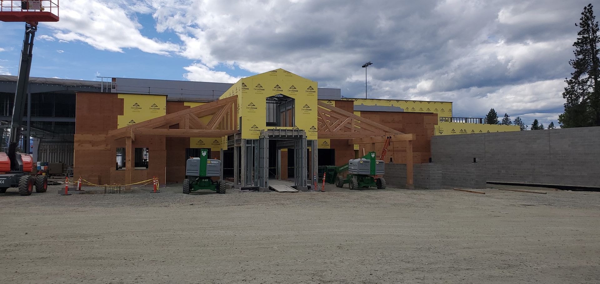 Brick storefront under construction with yellow facade, gray walls, and cloudy sky