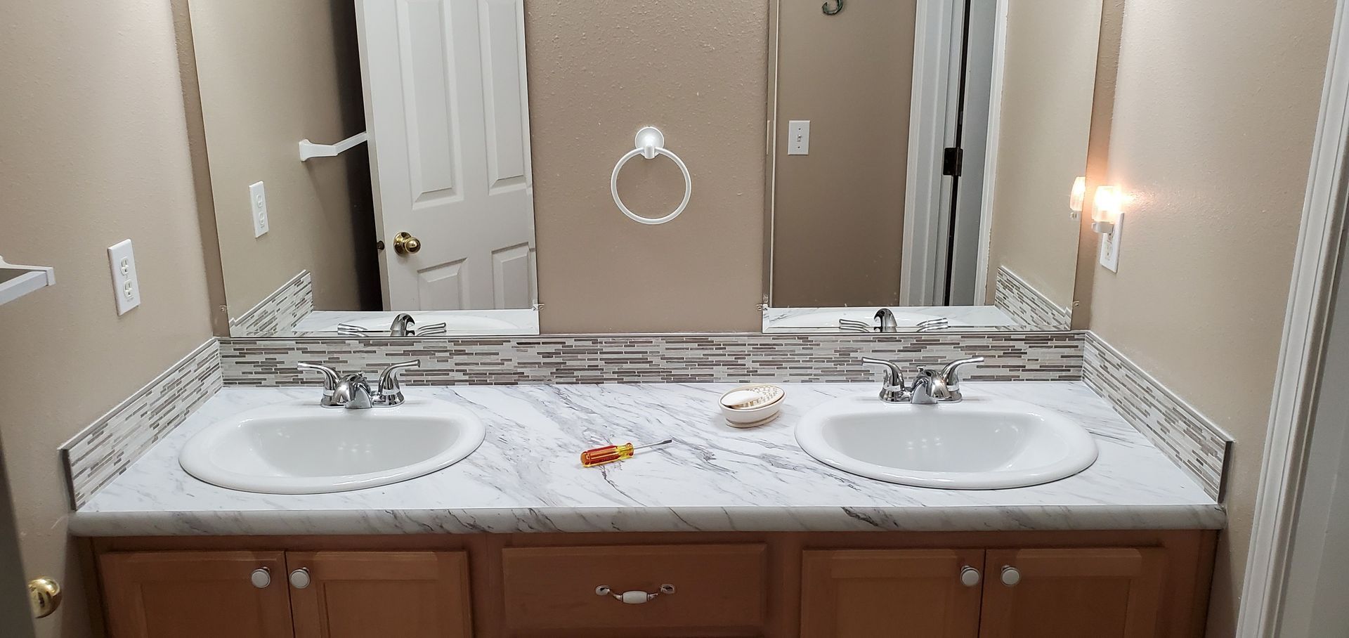 Bathroom vanity with double sinks, mirror, and beige walls in a hotel-style room