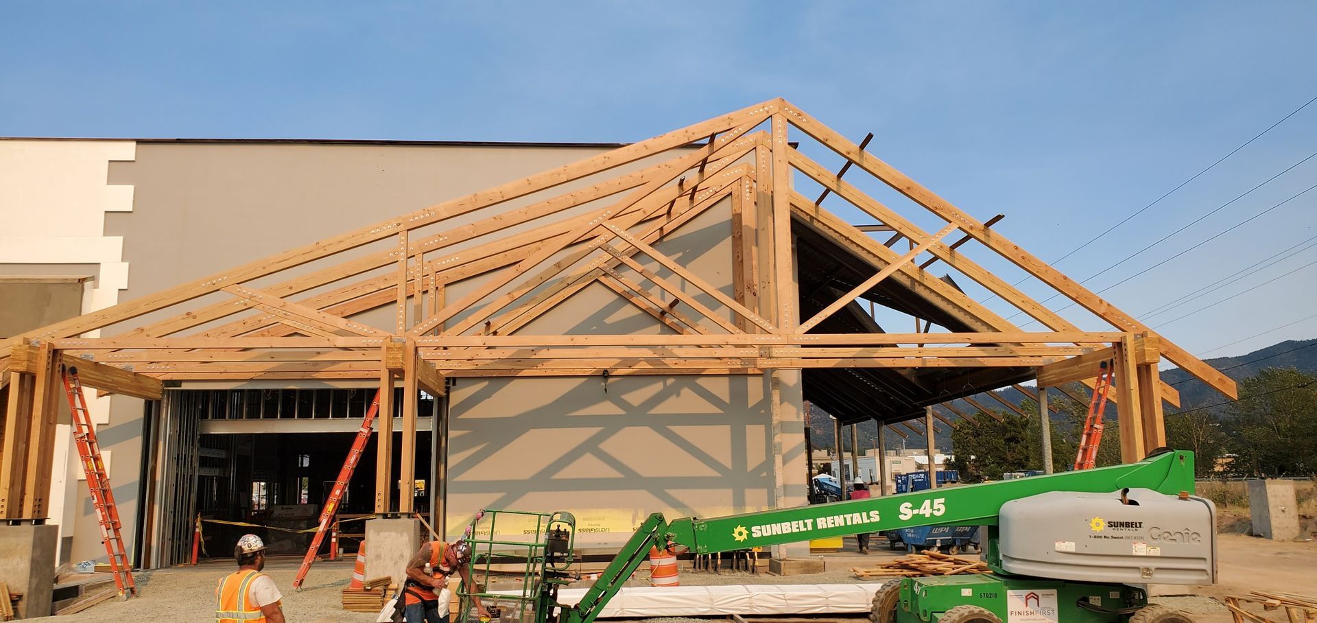 Construction site with roof trusses being installed on a building under construction