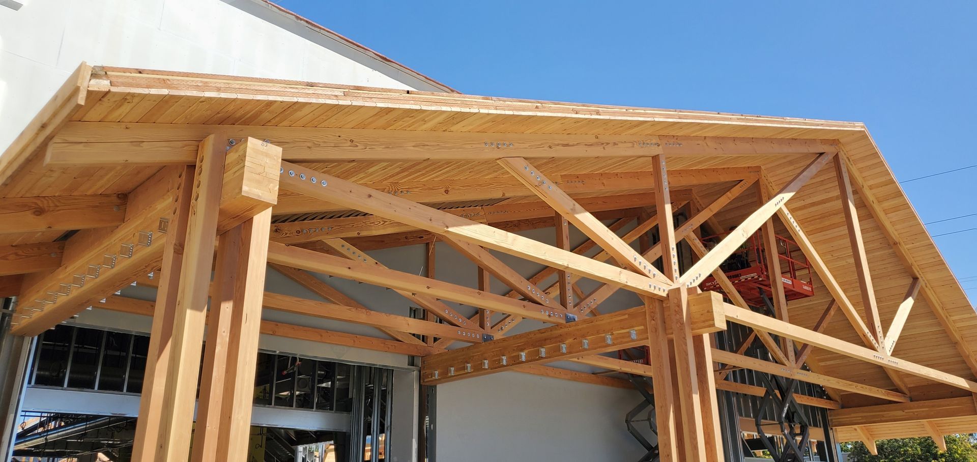 Wooden pergola-style awning over a building entrance with exposed beams and columns
