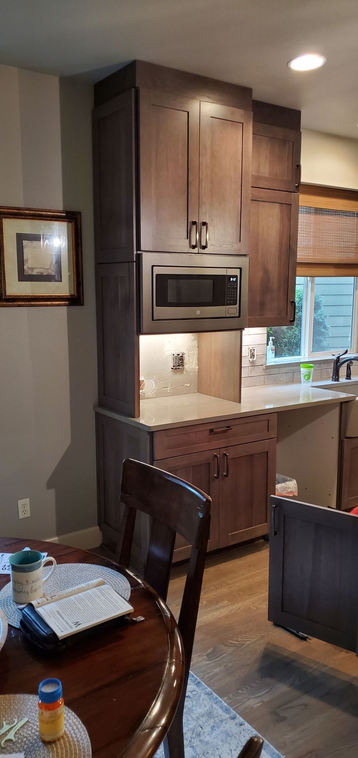 Kitchen nook with dark wood cabinets, built-in microwave, small dining table, and window blinds