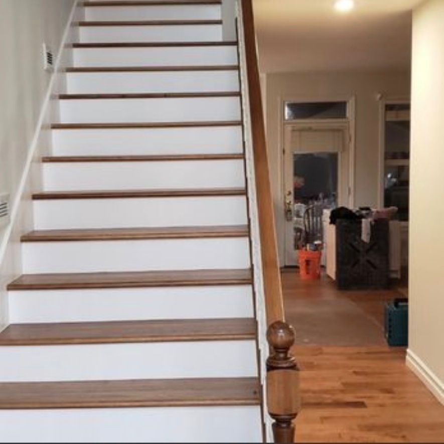 Interior staircase with white risers and wooden treads leading into a hardwood-floored hallway.