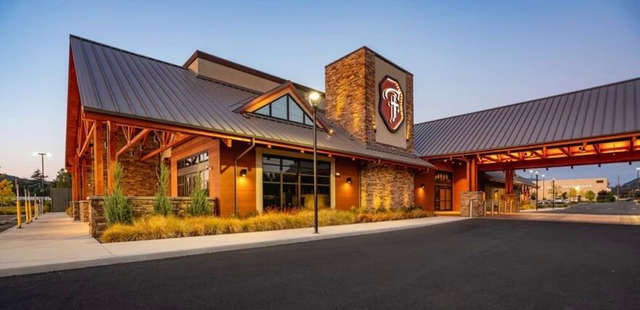 Rustic lodge-style building at dusk with timber beams, stone accents, and a covered entrance under a blue sky