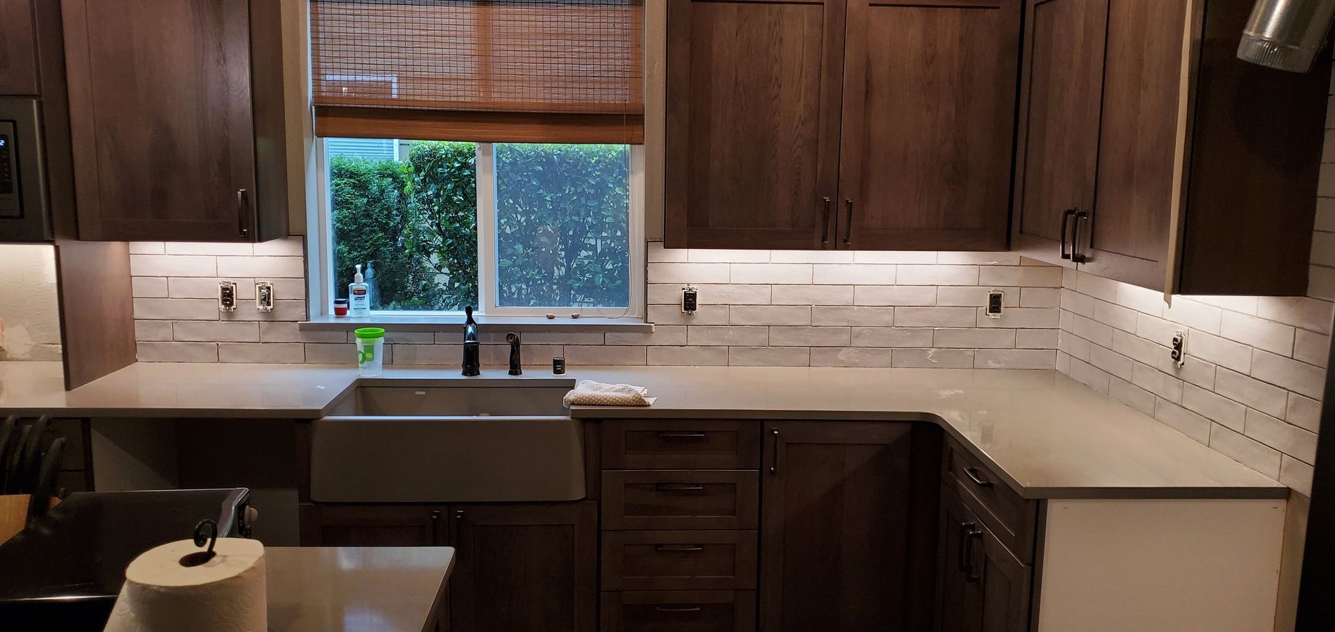 Modern kitchen with dark wood cabinets, white countertops, and a window over the sink