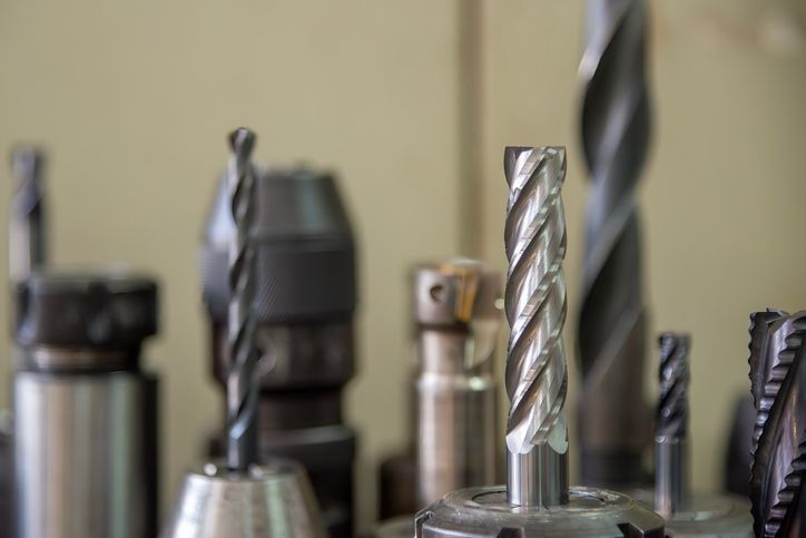 Close-up of assorted metal drill bits and tools, some with spiral flutes, in a workshop.