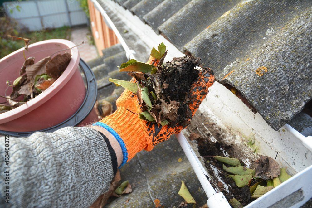 person cleaning gutters