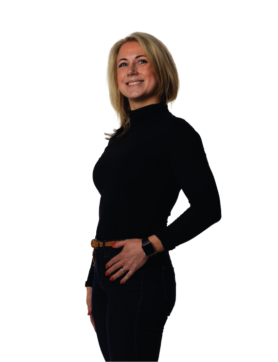 Woman in black turtleneck and jeans, smiles and poses, hand on hip.