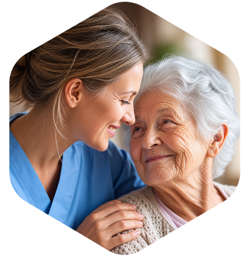 Nurse in blue gently comforts an elderly woman, both smiling closely in a warm, caring moment