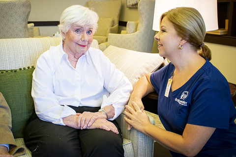Two women sitting on a couch, smiling and talking in a living room