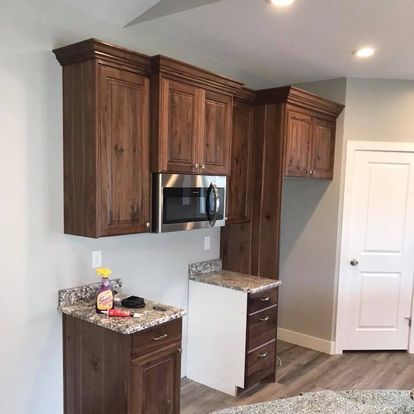 A kitchen with wooden cabinets , granite counter tops , stainless steel appliances and a microwave.