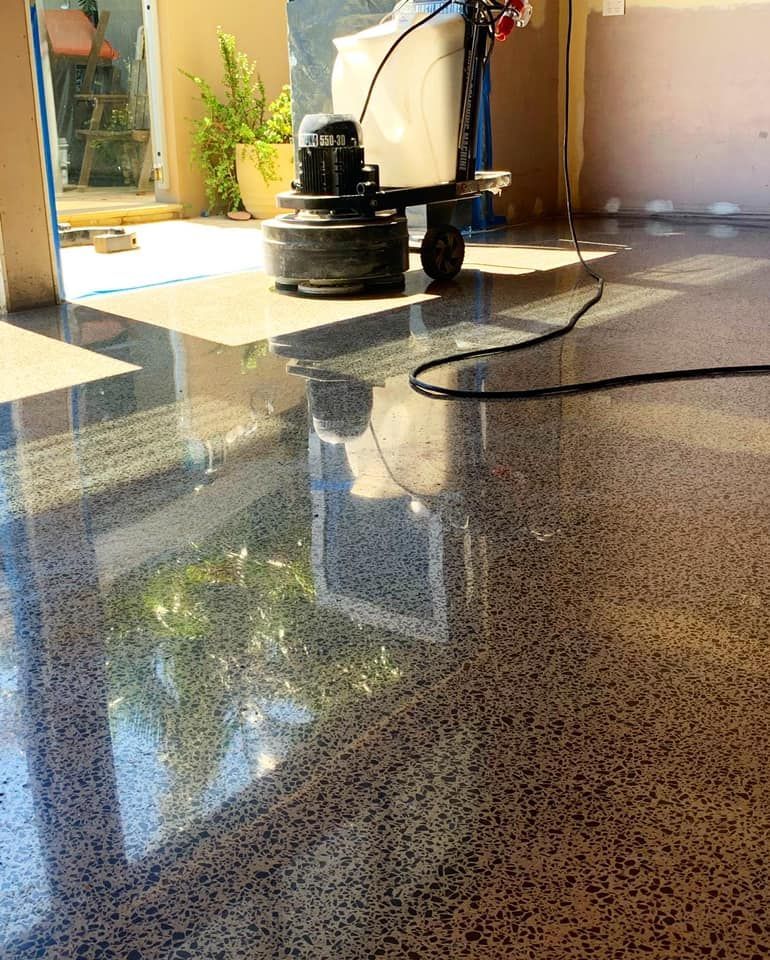 Polished concrete floor reflecting sunlight, with a floor grinder in the background. โ Showcase Concrete & Polishing in Moore Park Beach, QLD
