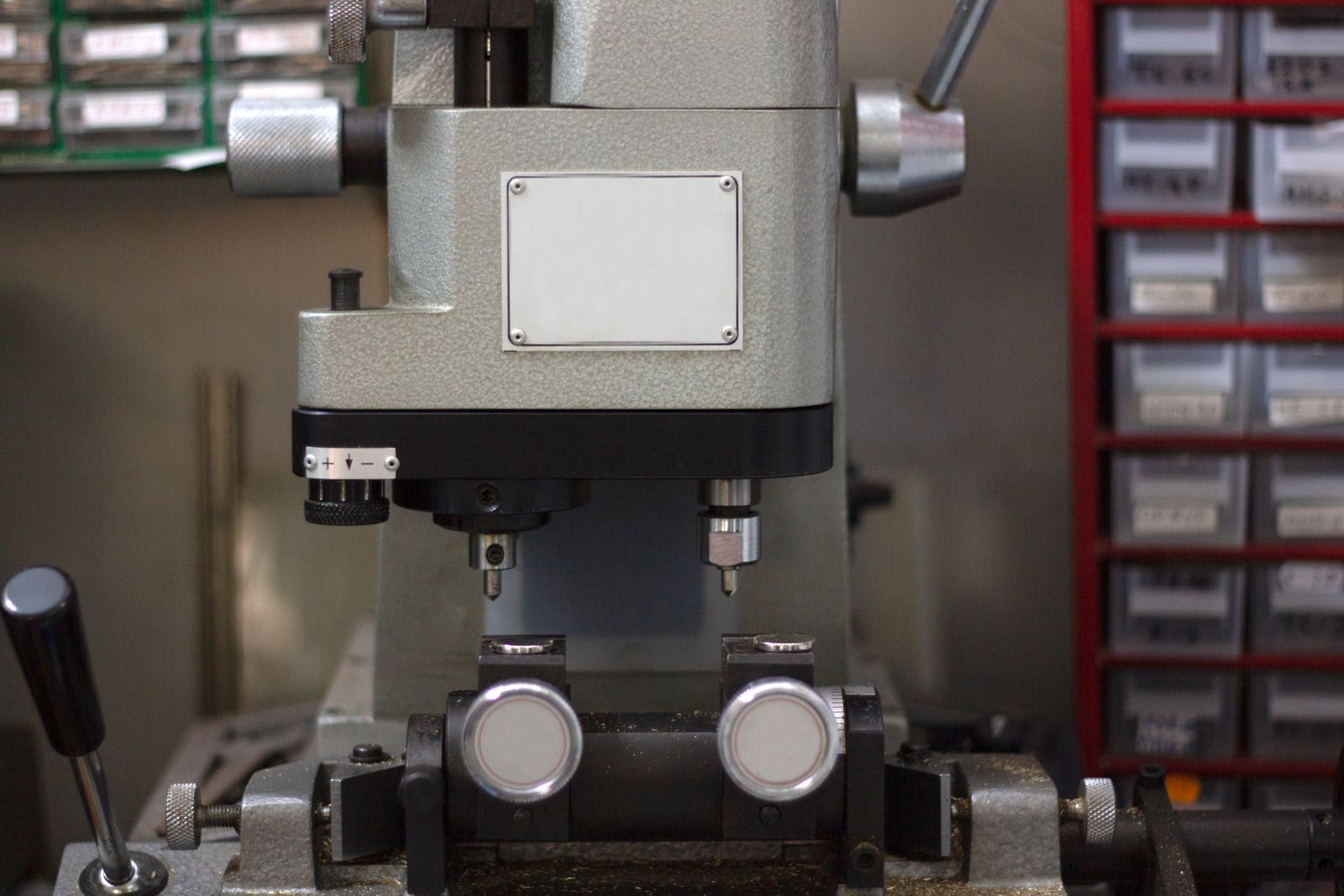 Close-up of a gray industrial machine with dials and clamps in a workshop setting