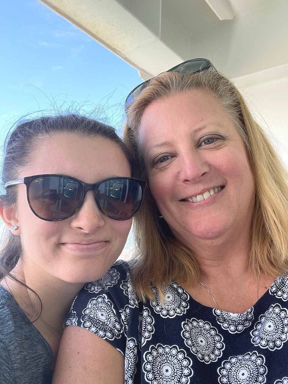 Two women wearing sunglasses are posing for a picture together.
