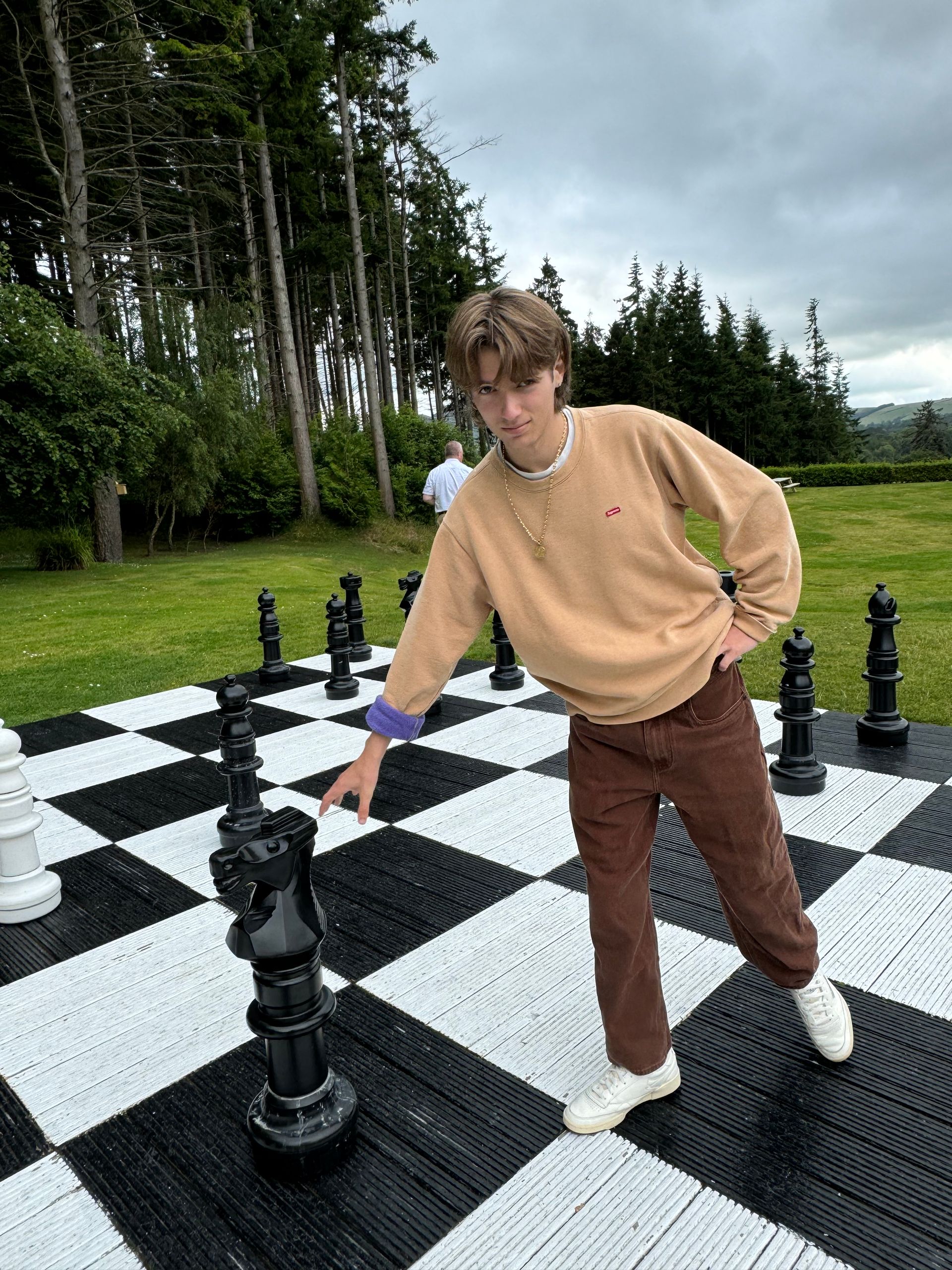 A young man is standing on top of a giant chess board.