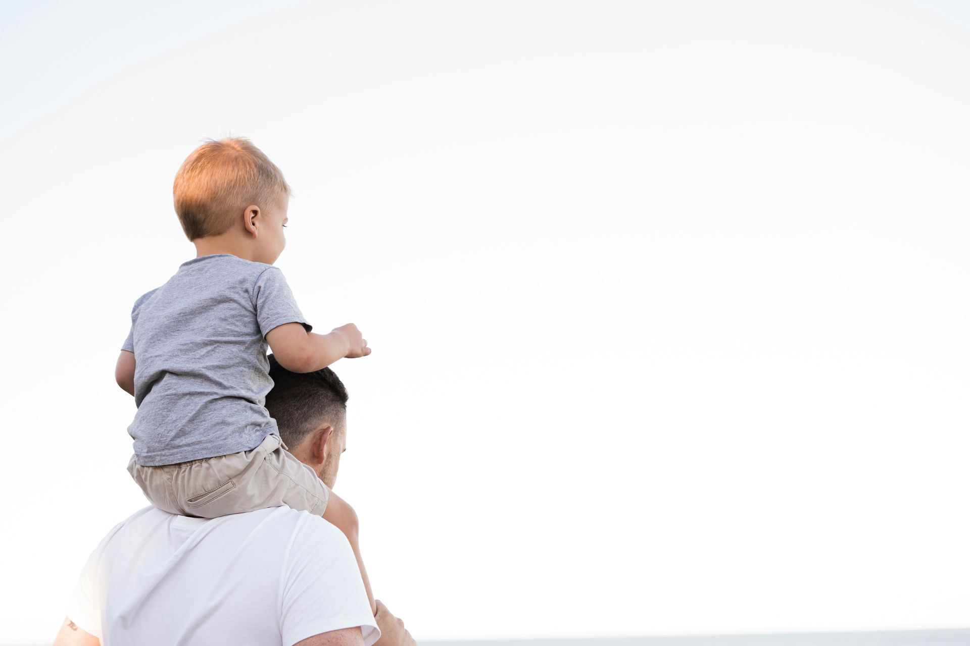 A man is carrying a baby on his shoulders.