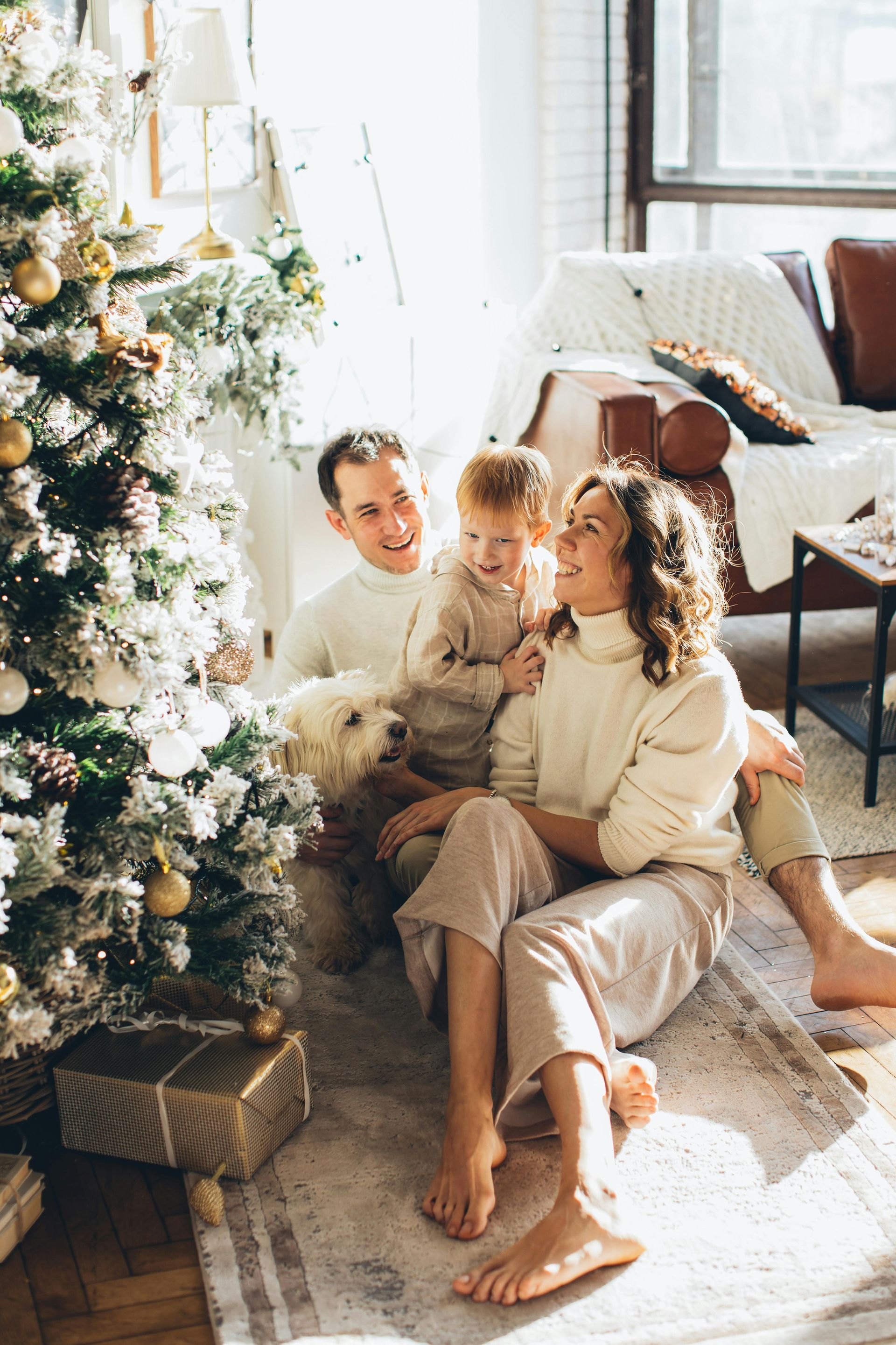 A family is sitting on the floor in front of a christmas tree.