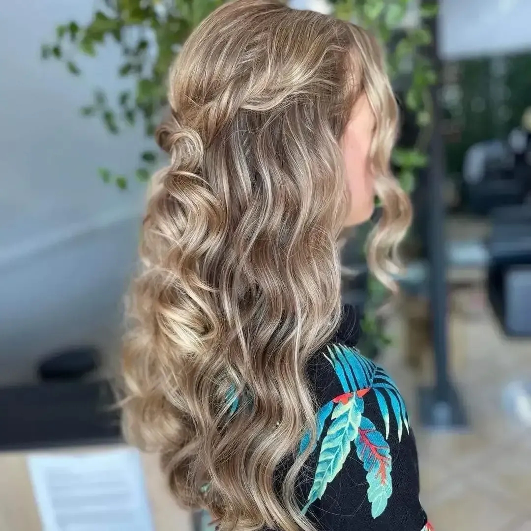 A Woman With Blonde Hair Is Standing In Front Of A Plant — M & Co Hair Salon In Atherton, QLD