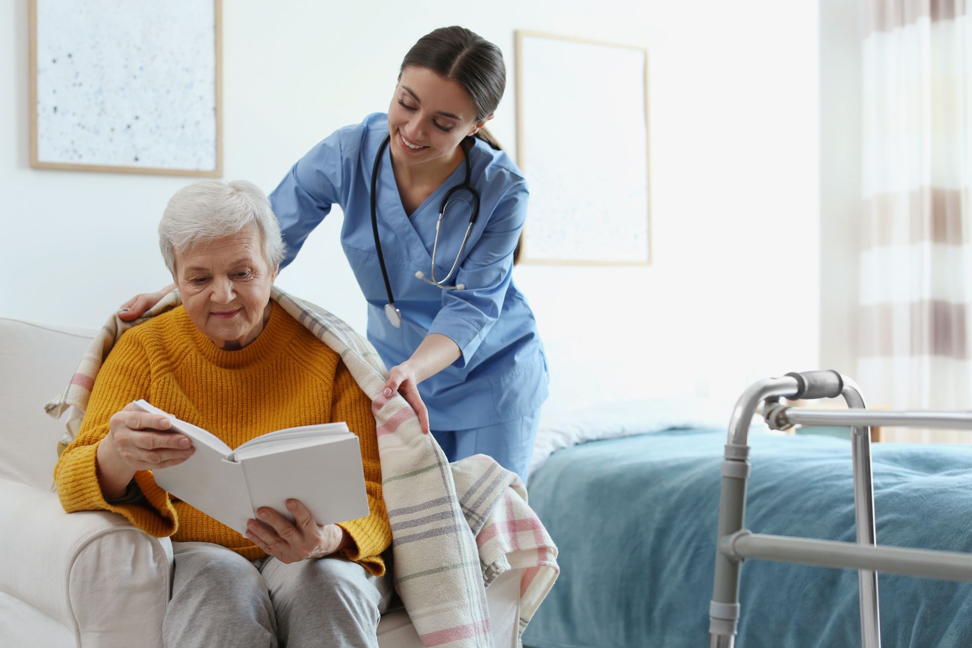 Nurse helping a patient read a book beside a hospital bed