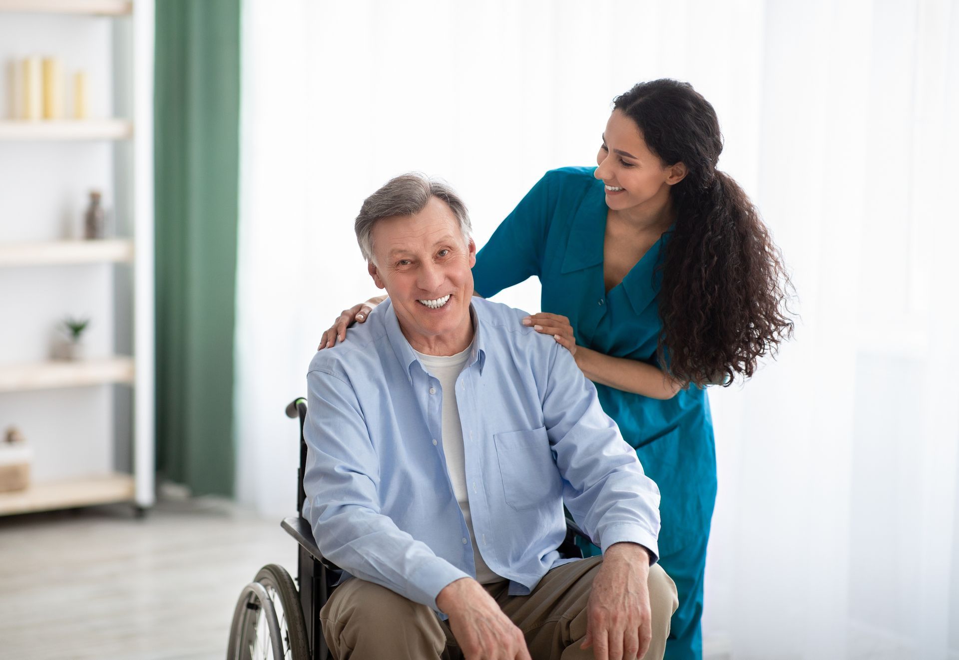 Caregiver massaging a smiling man in a wheelchair in a bright room