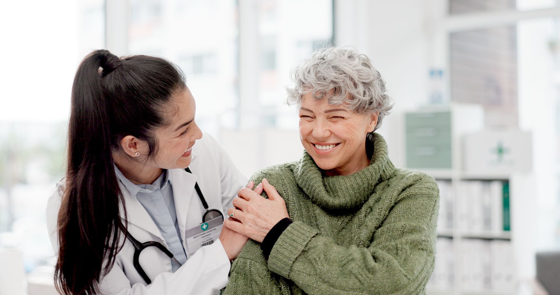 Nurse smiling and comforting a patient in a bright clinic, holding her arm