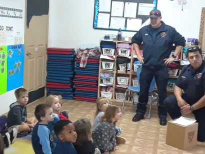 Two police officers are talking to a group of children in a room