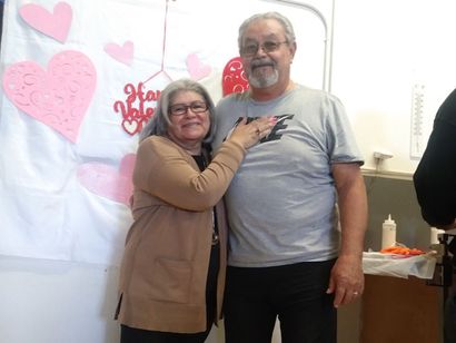 A man and woman are posing for a picture in front of a sign that says happy valentine 's day