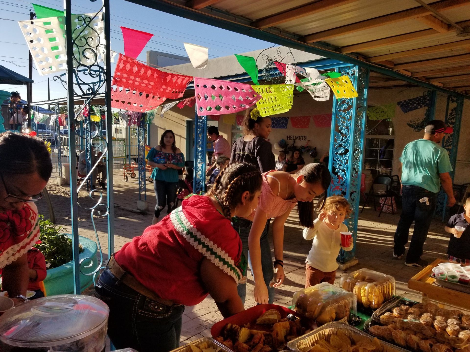 A group of people are standing around a table looking at food.