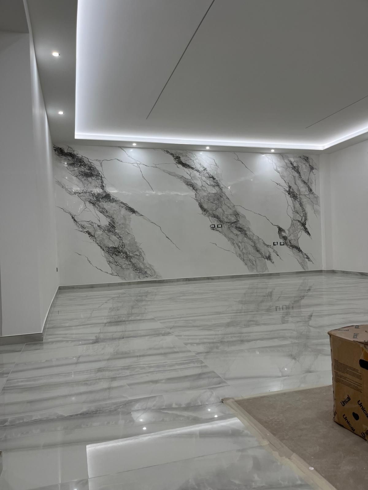 Bagno in costruzione; pannelli bianchi e grigi sulle pareti, tubature a vista.