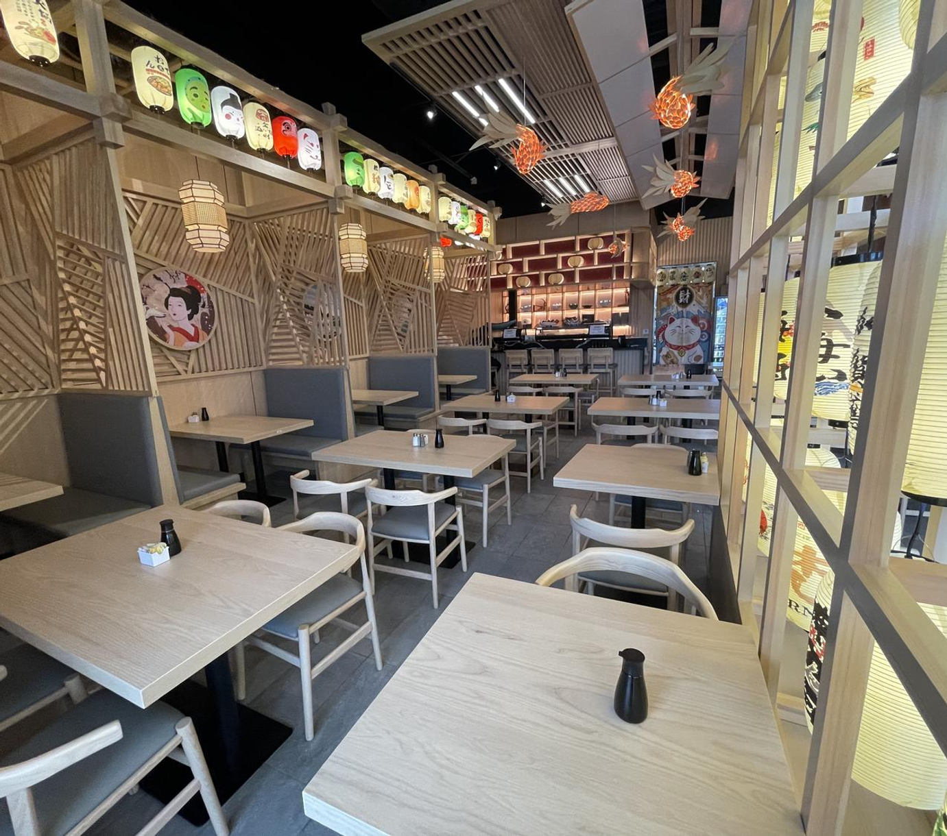 Modern cafe interior with light wood tables, woven chairs, and warm hanging lanterns