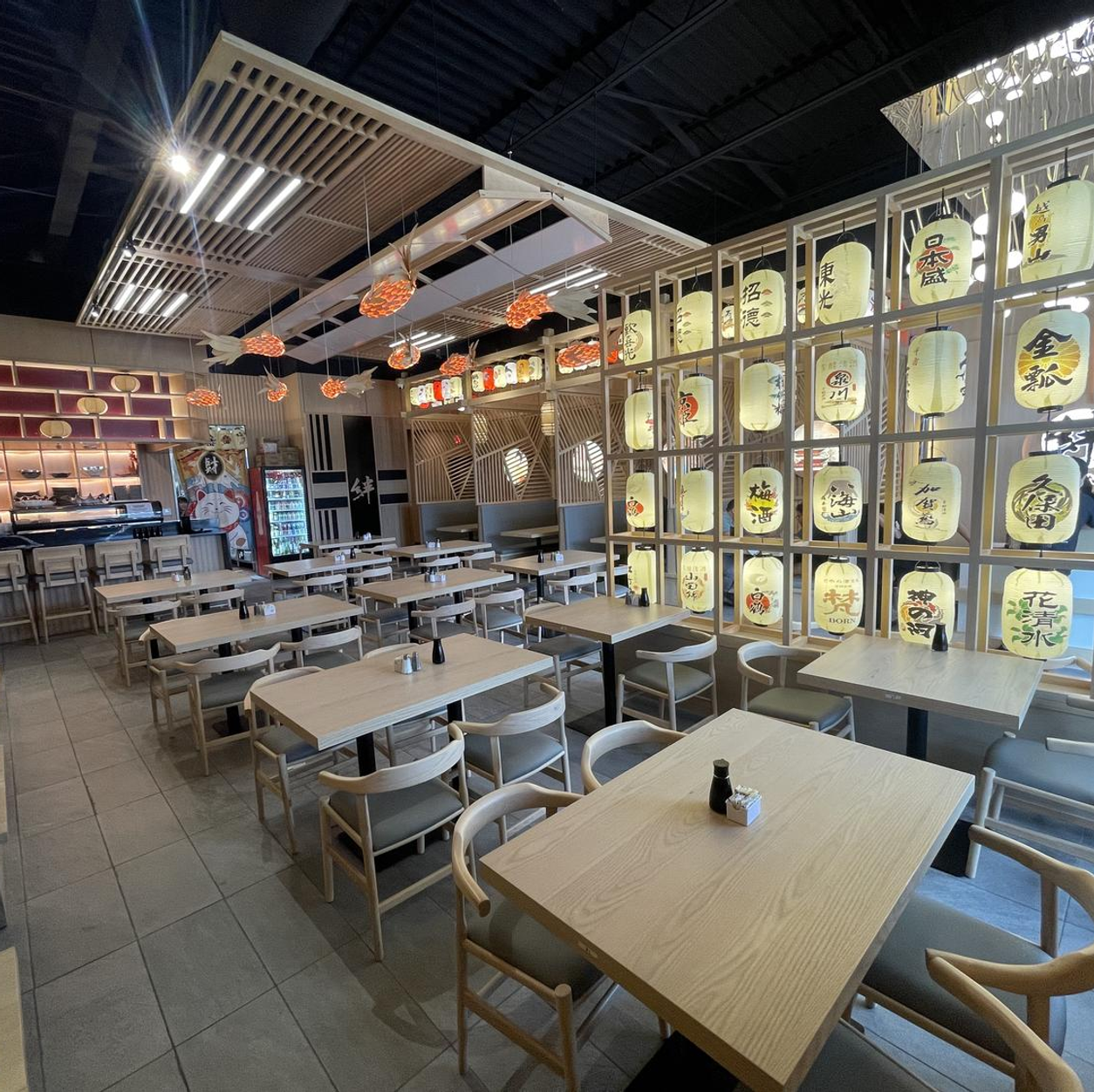 Empty modern restaurant interior with wooden tables, metal chairs, and illuminated wall art panels