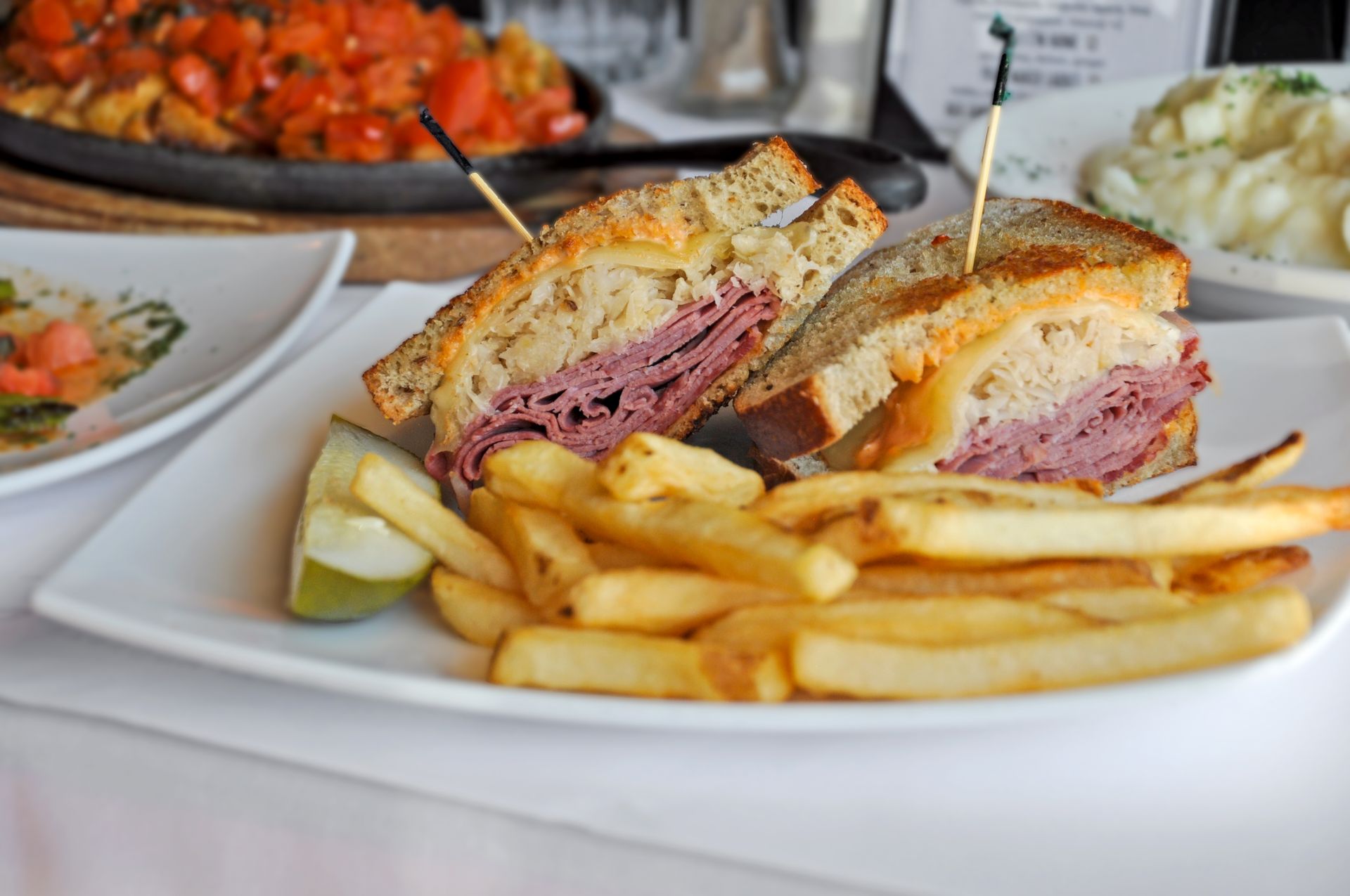 A sandwich and french fries on a white plate on a table.