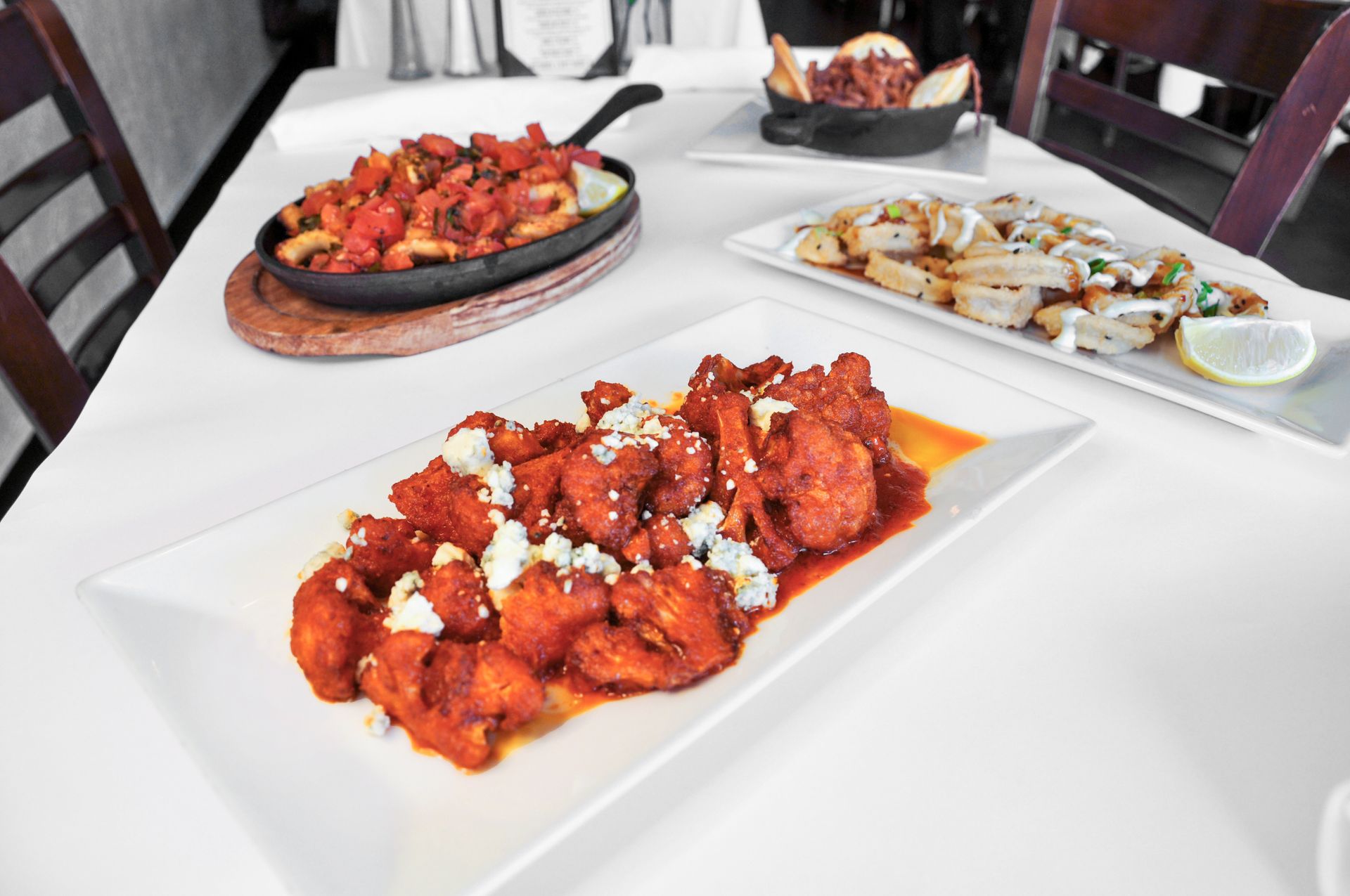 Three plates of food are sitting on a white table.