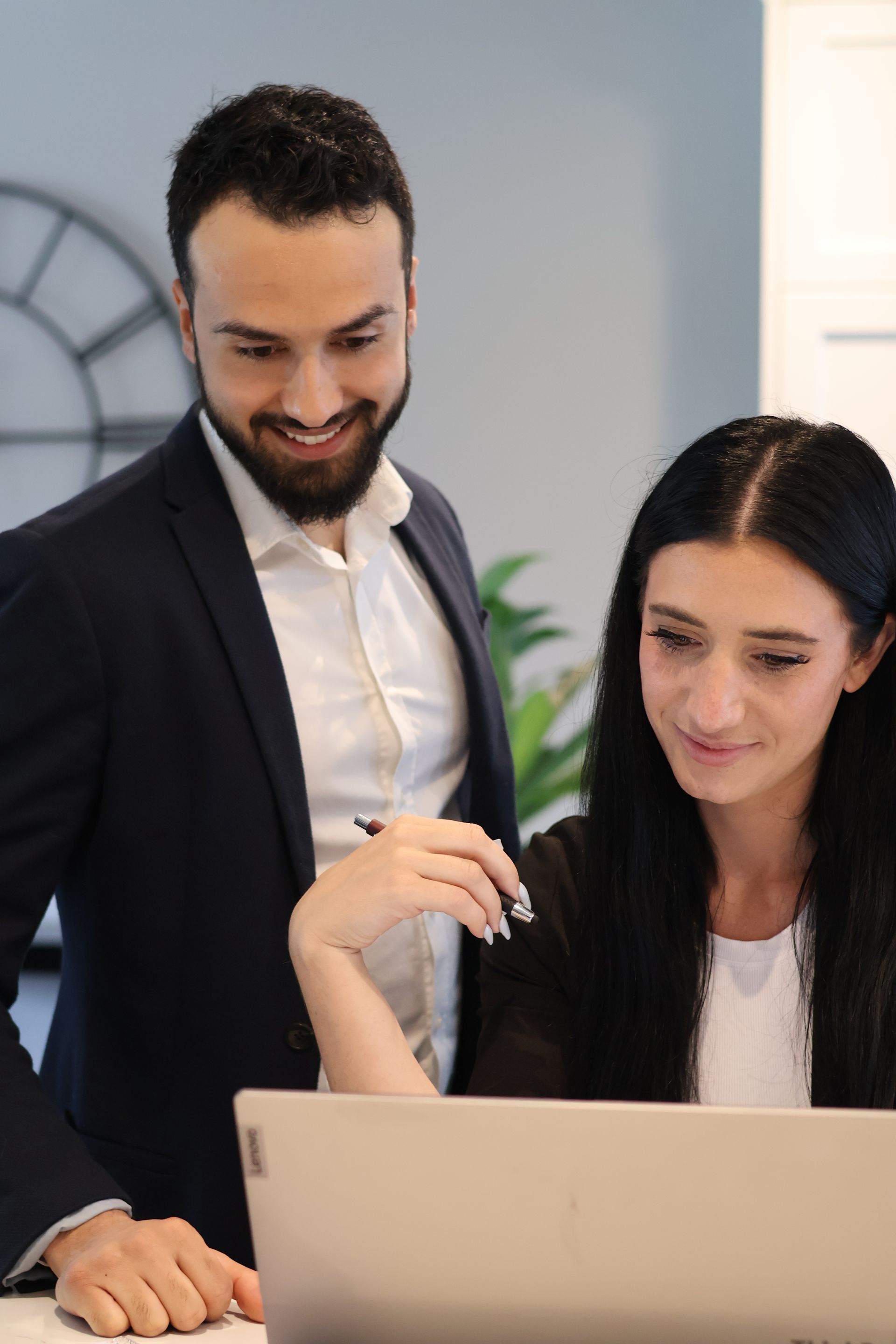 a man and a woman are looking at a laptop computer .