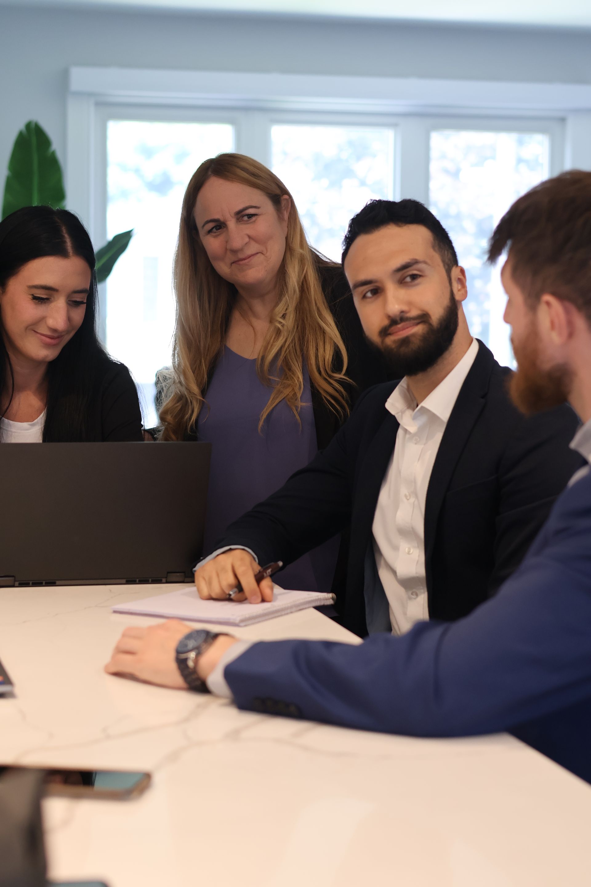 a group of people are sitting around a table having a meeting .