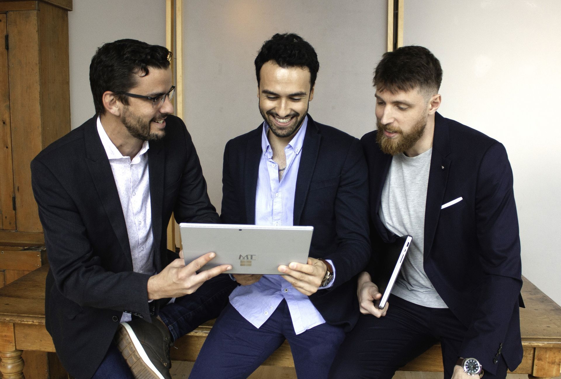 Three businesspeople in suits sitting together and looking at a laptop in a conference room
