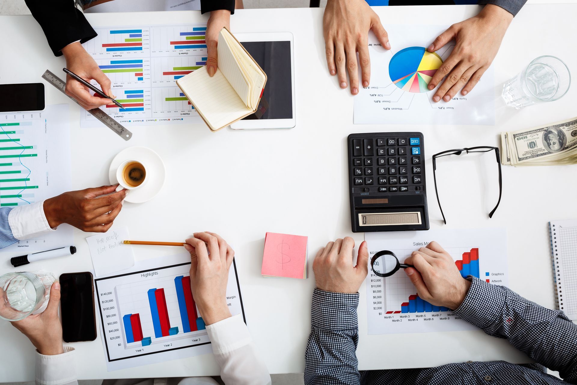 a group of people are sitting around a table looking at charts and graphs .