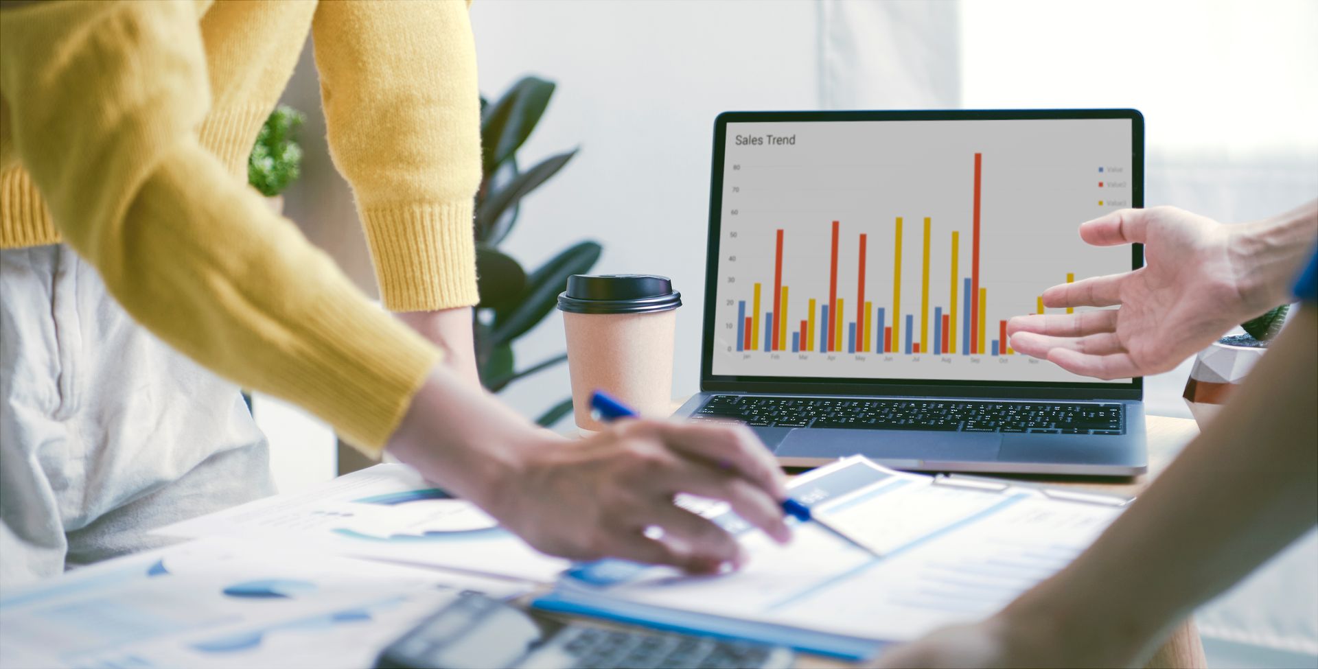 People reviewing charts and graphs on a laptop during a meeting
