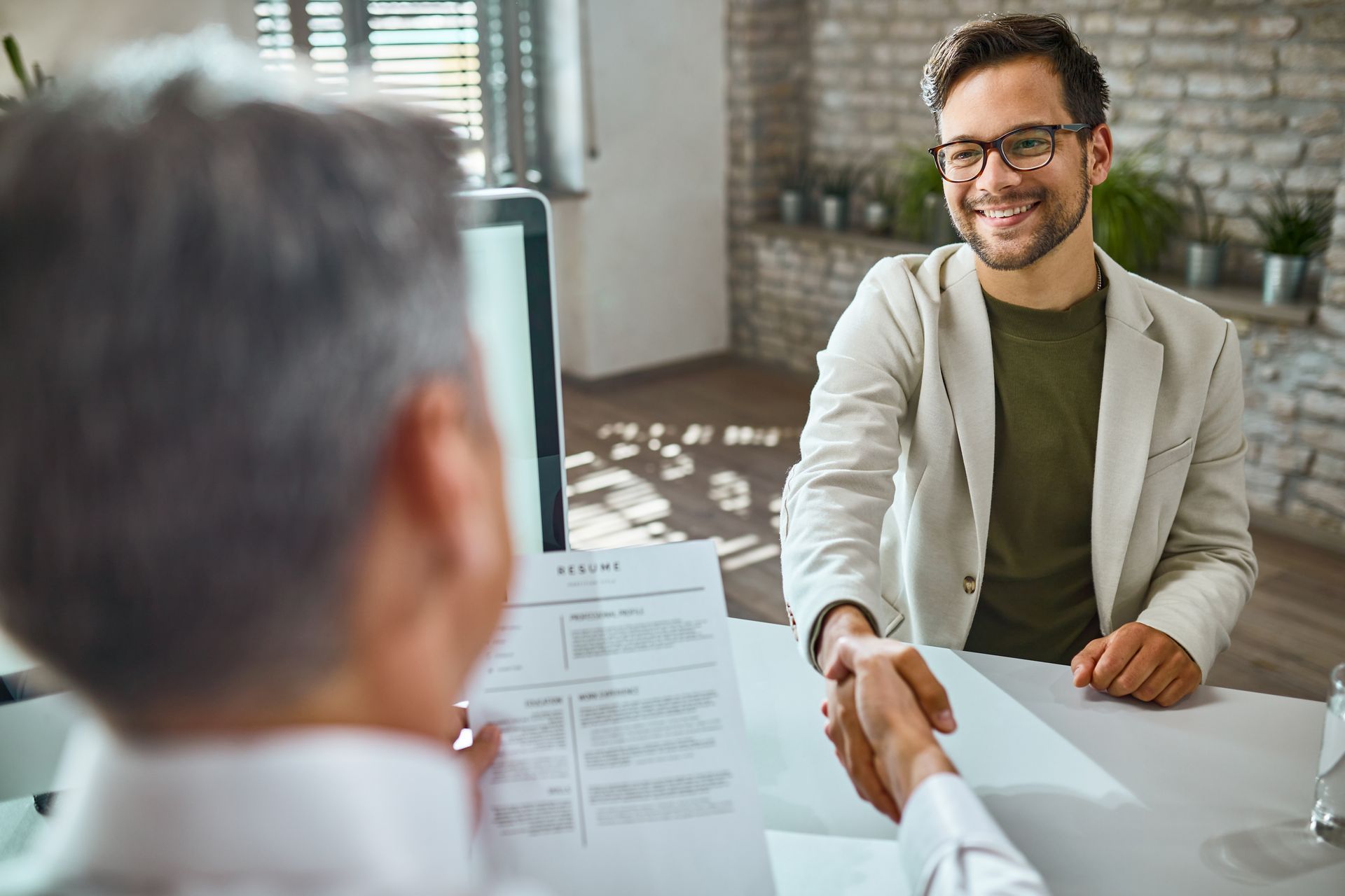 a man is shaking hands with another man during a job interview .
