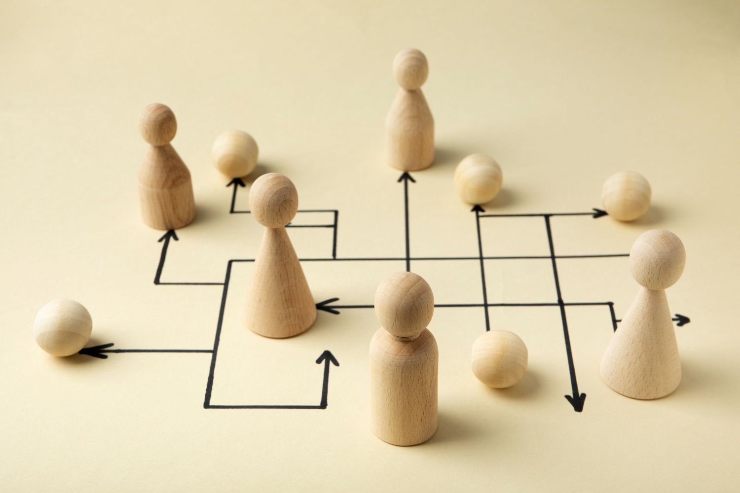 a group of wooden figurines are sitting in a maze with arrows pointing in different directions .