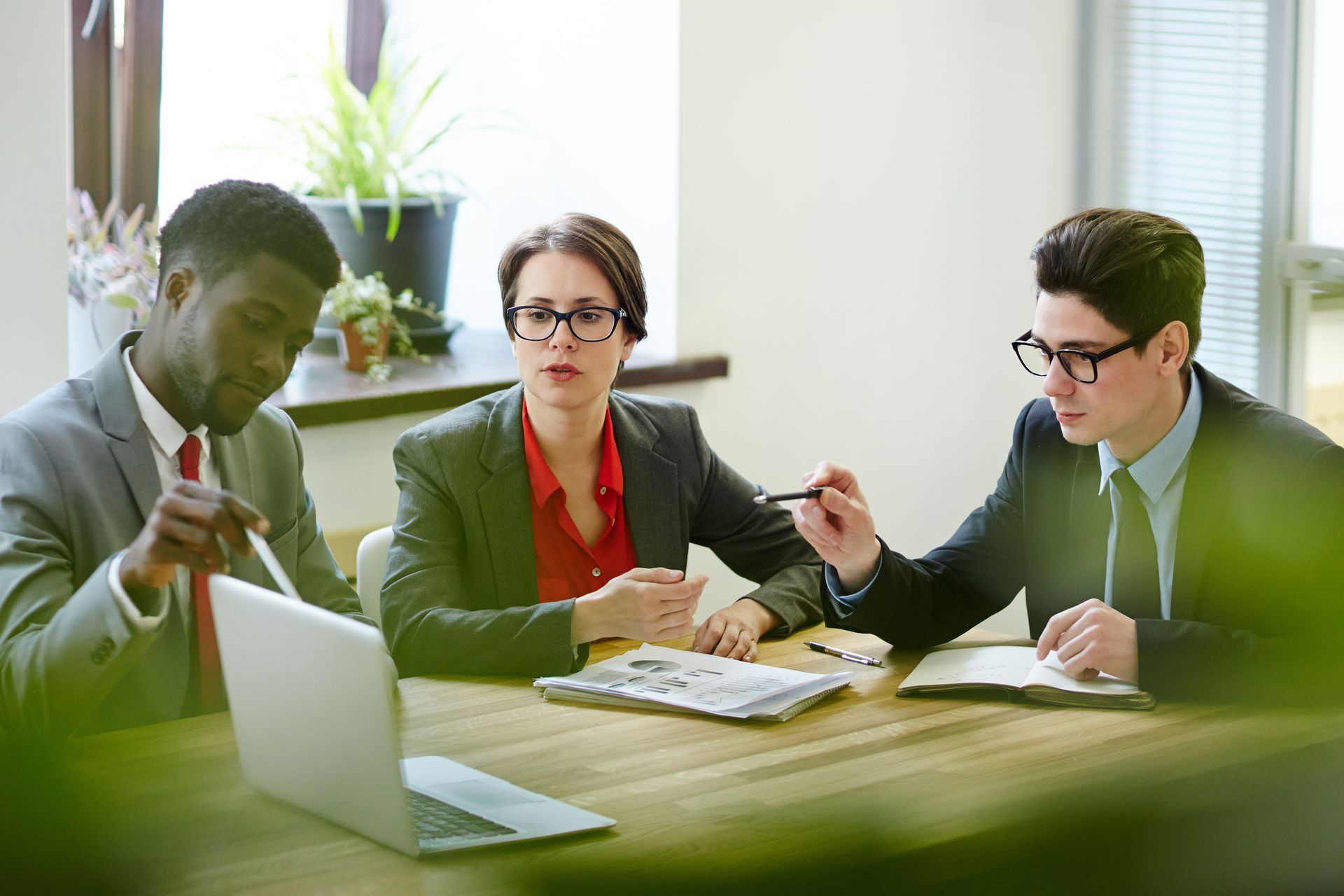 a group of business people are sitting at a table with a laptop .