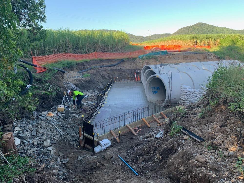 A Group of Construction Workers Are Working on A Large Pipe in The Dirt — Mass Construction Group Australia Pty Ltd in South Mackay, QLD