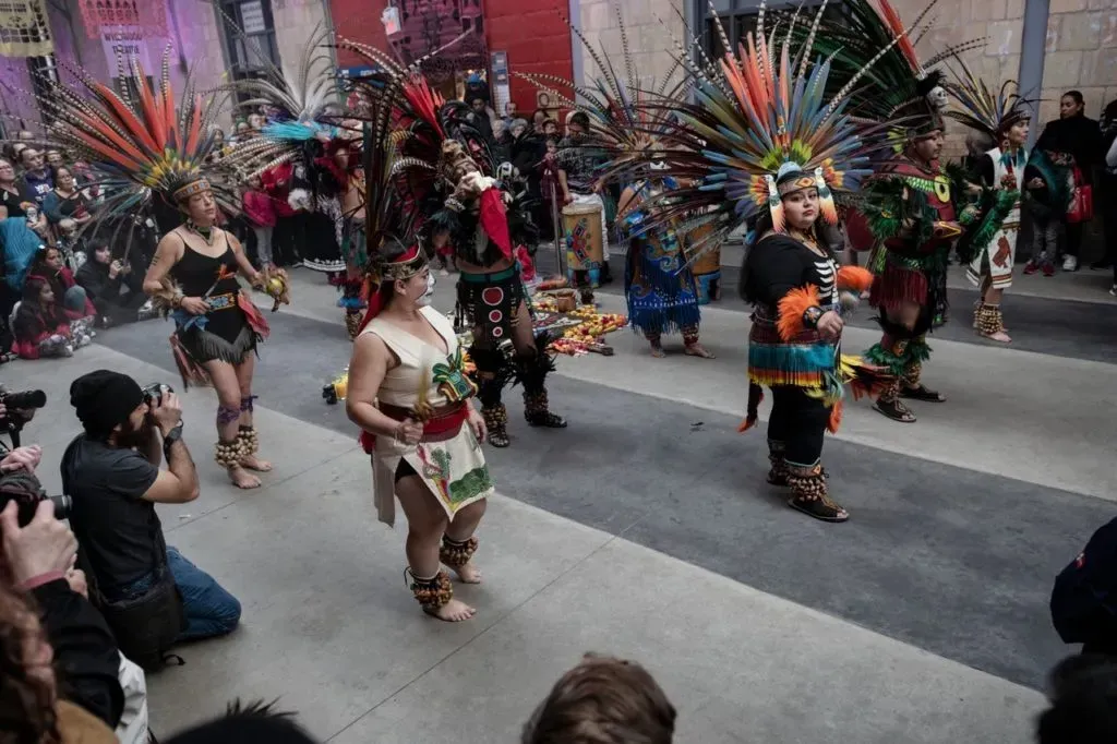 A group of people dressed in colorful costumes are dancing on a street.